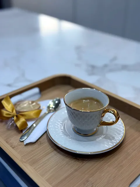 Xícara de café servida em bandeja de bambu, com bombom