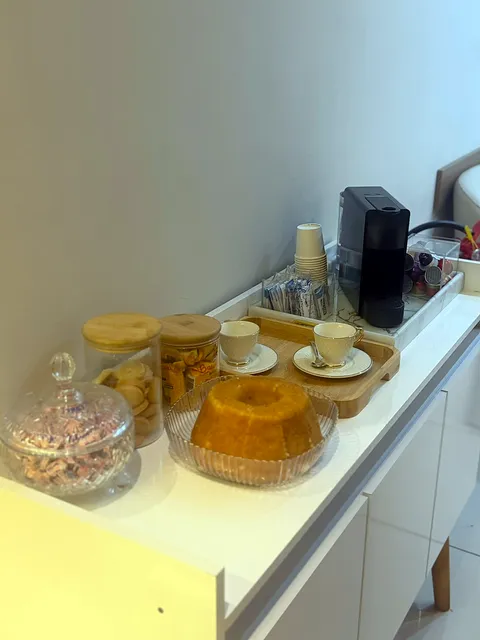 Cantinho do café com máquina de cápsulas, bolo e biscoitos